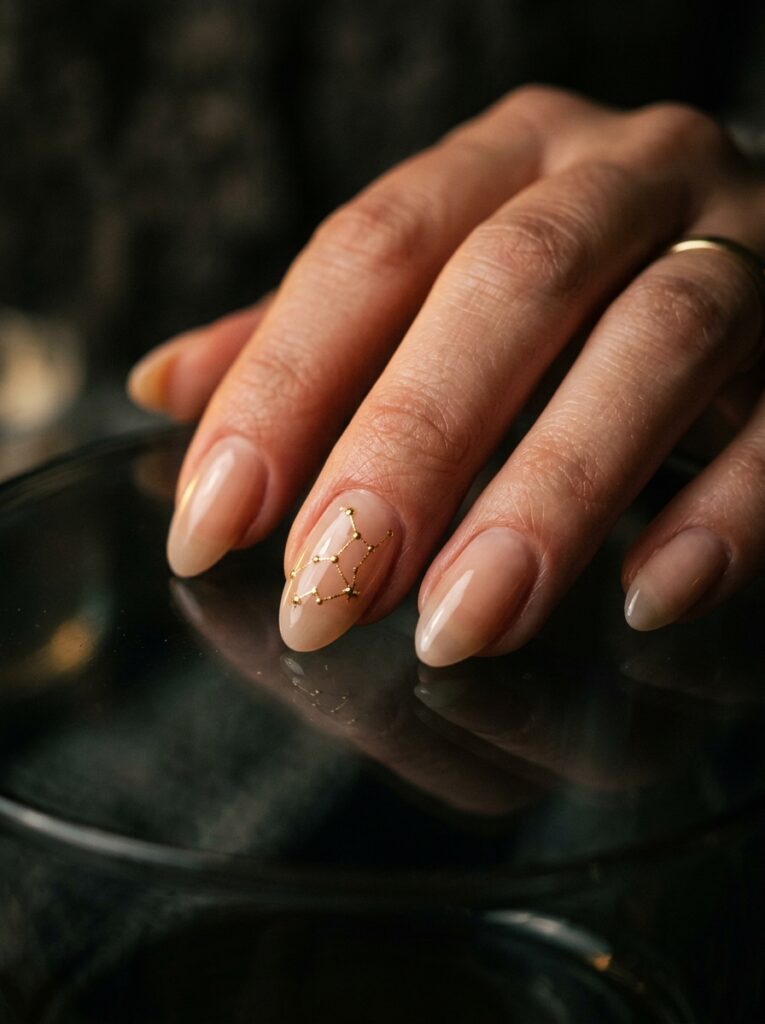 gold virgo constellation nail art on sheer nude base